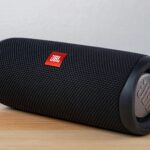 Close-up of a modern wireless speaker on a wooden table, highlighting sleek design.