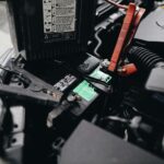 Detailed view of a car battery being jump-started with cables in an engine bay.