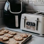 Freshly baked cookies on tray beside air fryer and toaster.