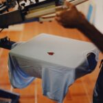 Close-up of a man using a T-shirt printing machine indoors.